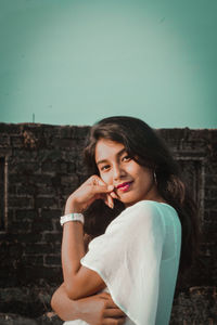 Portrait of beautiful woman against wall