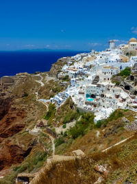 High angle view of townscape by sea against blue sky