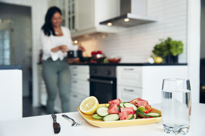 Salad on plate, woman in kitchen on background