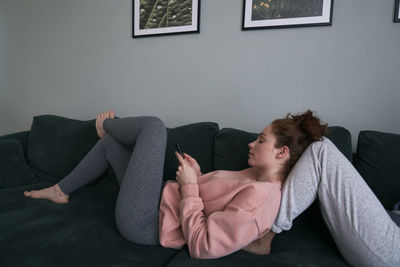 Young woman using phone on sofa at home