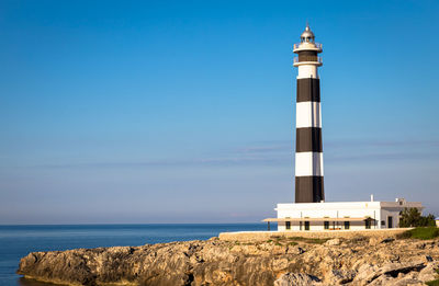 Lighthouse by sea against sky