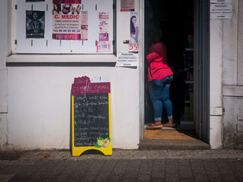 Rear view of woman standing at entrance of building