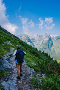 Rear view of man standing on mountain against sky