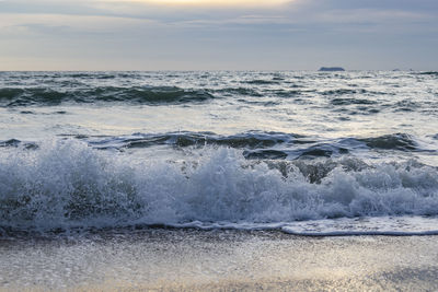 Waves splashing on shore against sky