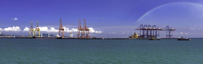 Commercial dock by sea against blue sky