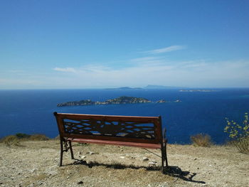 Empty chairs on beach against sky