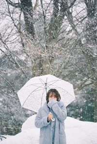 Man holding umbrella standing in snow