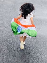 Rear view of girl holding indian flag running on road