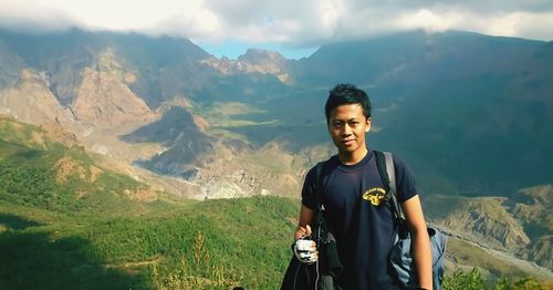 Portrait of young man standing against mountains