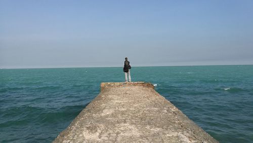 Mid distance view of person standing on pier against sky