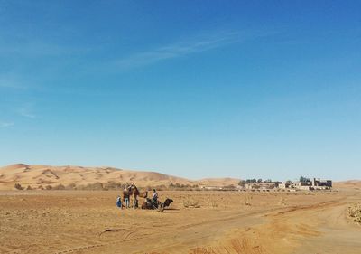 People on desert against clear blue sky