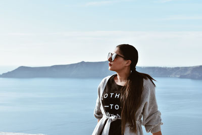 Young woman wearing sunglasses standing on mountain against sky
