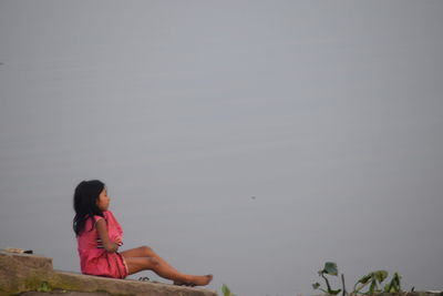 Girl sitting on rock by lake