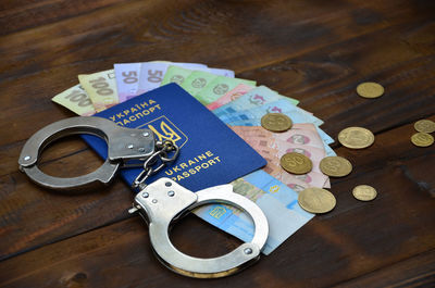 High angle view of handcuffs with passport and currency on table