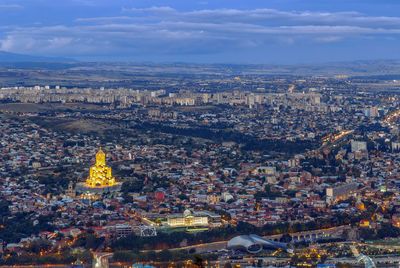 Aerial view of city buildings against cloudy sky