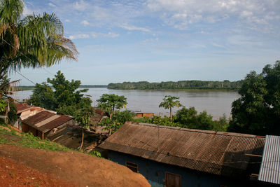 Houses and trees by plants and river against sky in bolivia