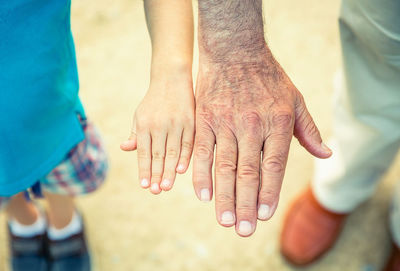 High angle view of man and boy comparing size of hands