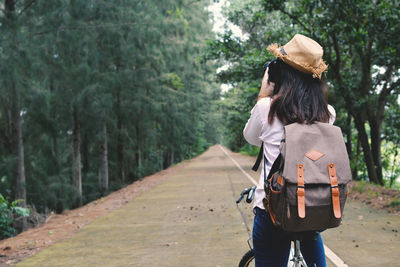Rear view of woman walking on road in forest