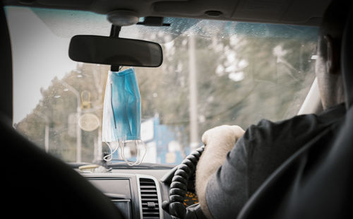 A medical mask hanging on a car mirror