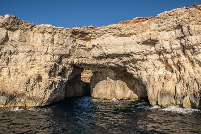 Rock formations in sea against clear sky