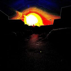 Illuminated road against sky at night