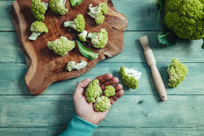 High angle view of hand holding vegetables on cutting board