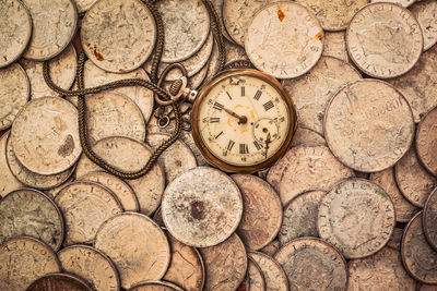 High angle view of pocket watch on coins