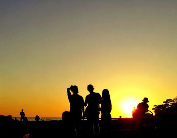 Silhouette people against orange sky during sunset