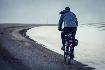 Rear view of man riding bicycle on road