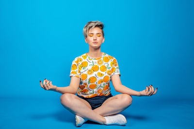 Full length of girl sitting against blue sky