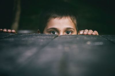 Portrait of boy hiding behind metal