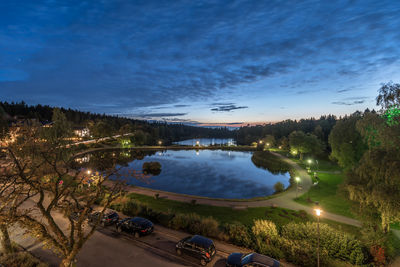 High angle view of illuminated trees by lake against sky