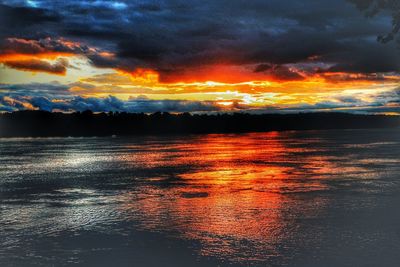 Scenic view of sea against dramatic sky during sunset