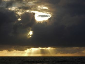Scenic view of sea against dramatic sky during sunset