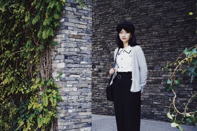 Young woman standing against brick wall