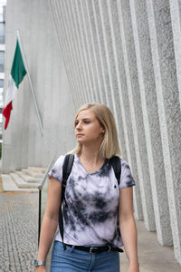Beautiful young woman standing against wall
