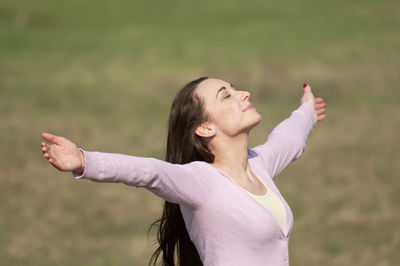High angle view of smiling mid adult woman with arms outstretched standing on grassy field in park