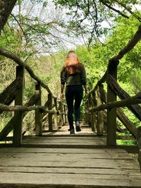 Rear view of woman walking on footbridge