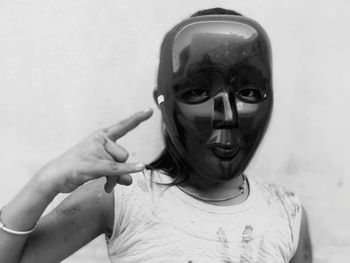 Portrait of young woman wearing mask against wall