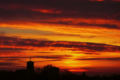 Silhouette building against dramatic sky during sunset