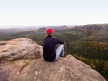 Rear view of man sitting on rock