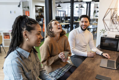 Businesswoman laughing with colleagues in coffee break at office