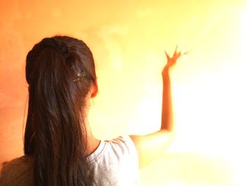 Rear view of woman against orange wall