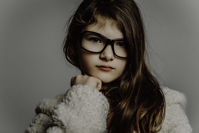 Close-up portrait of cute girl wearing eyeglasses against gray background