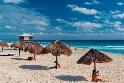 Lounge chairs and parasols on beach against sky