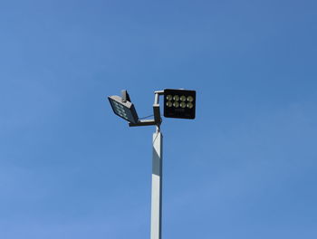 Low angle view of road sign against clear blue sky