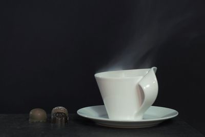 Close-up of coffee cup on table against black background