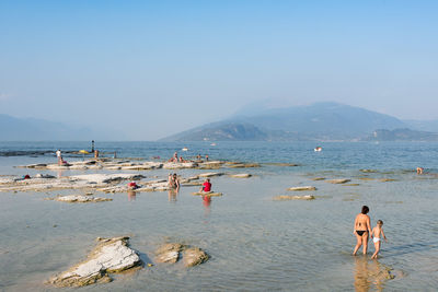 People on beach against clear sky