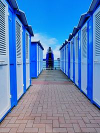 Rear view of man walking on footpath amidst buildings