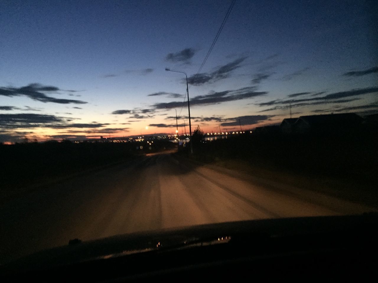 ROAD SEEN THROUGH CAR WINDSHIELD DURING SUNSET